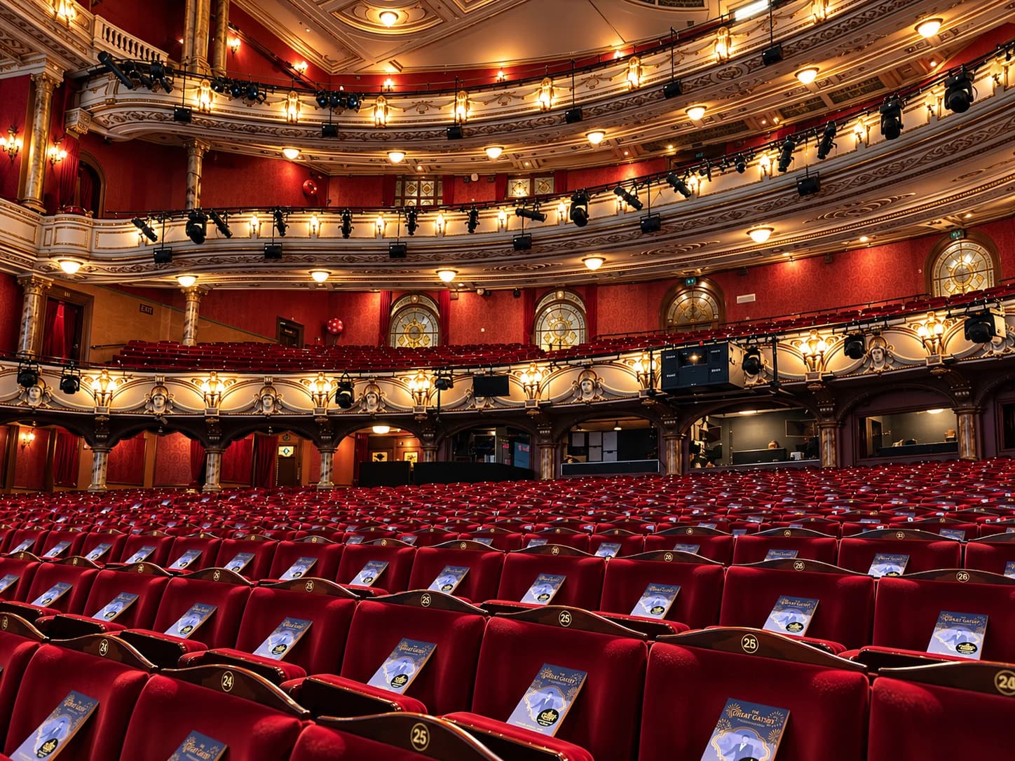 Wide view of the London Coliseum with paperback books arranged across rows of red seats.